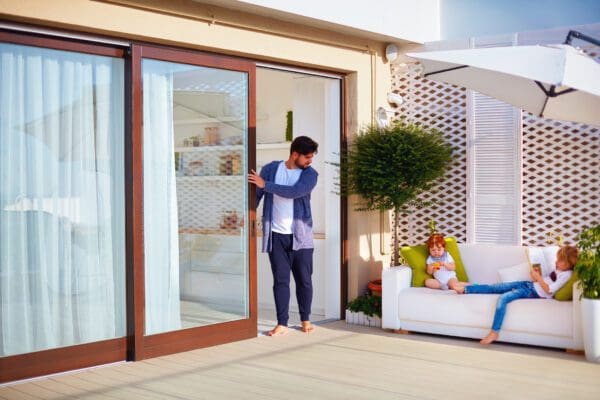 man opening sliding glass door to deck
