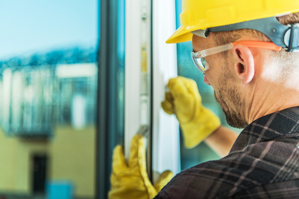 A professional replacing an especially complex window, which can leave homeowners asking how much to tip window installers who go above and beyond