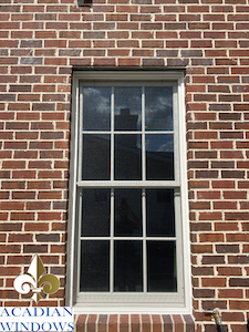 Our Chickasaw Window Company represented by a photo of a window on a brick building with the Acadian Windows logo.