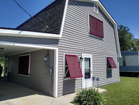 We provide hurricane shutters Mobile AL can rely on, such as these attractive maroon Bahama shutters on a local customer's home