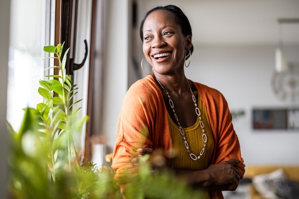 A happy woman standing at her energy-efficient window, one of the best windows for Gulf Coast summers